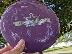 Dynamic Discs Treason in front of a tree